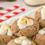 Hot chocolate cookies with three toasted mini marshmallows on top of each cookie on a plate.