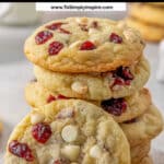 White chocolate cranberry cookies neatly stacked on top of each other with one leaning on the stack.