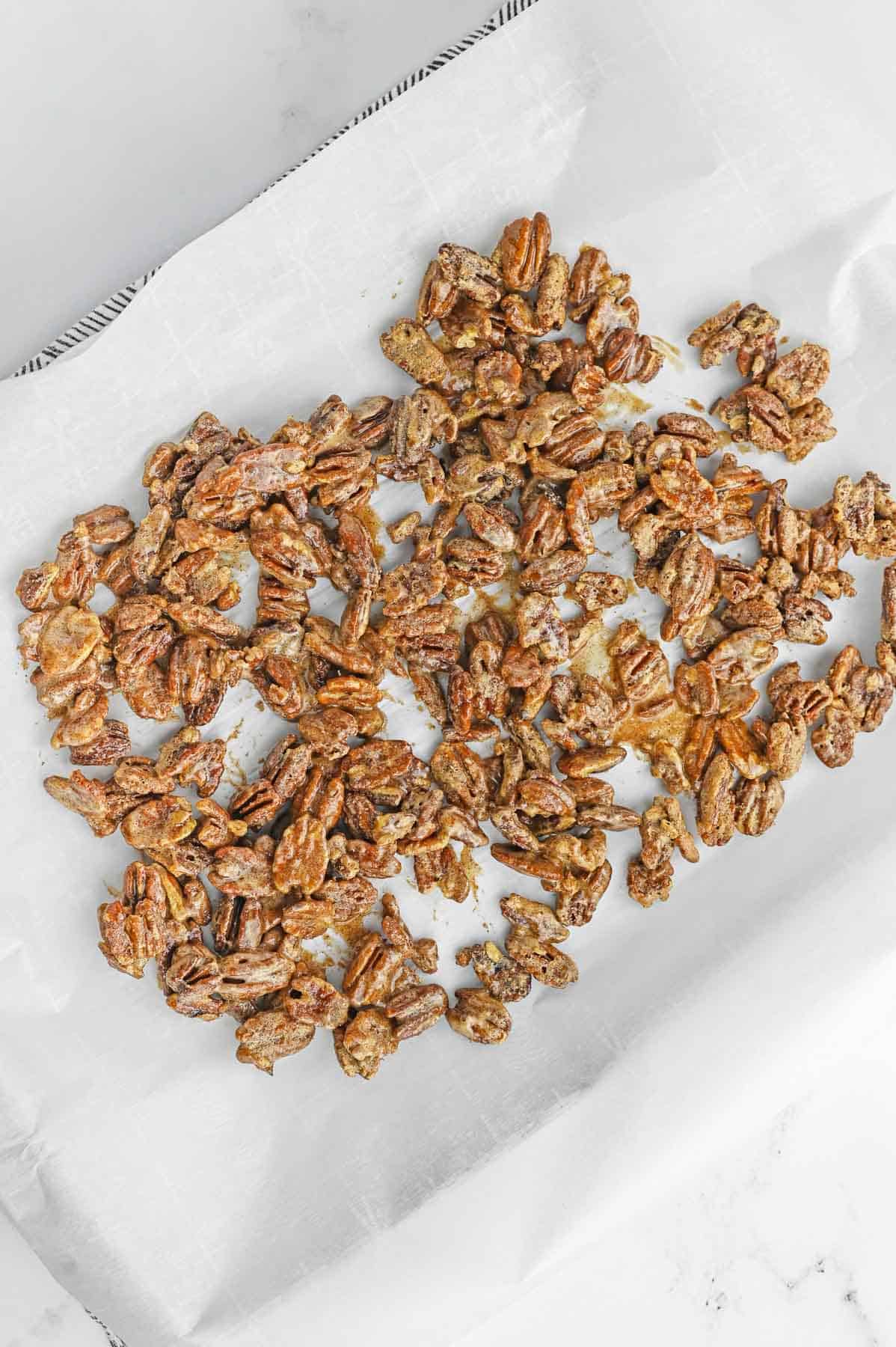 candied pecans on a sheet of parchment paper.