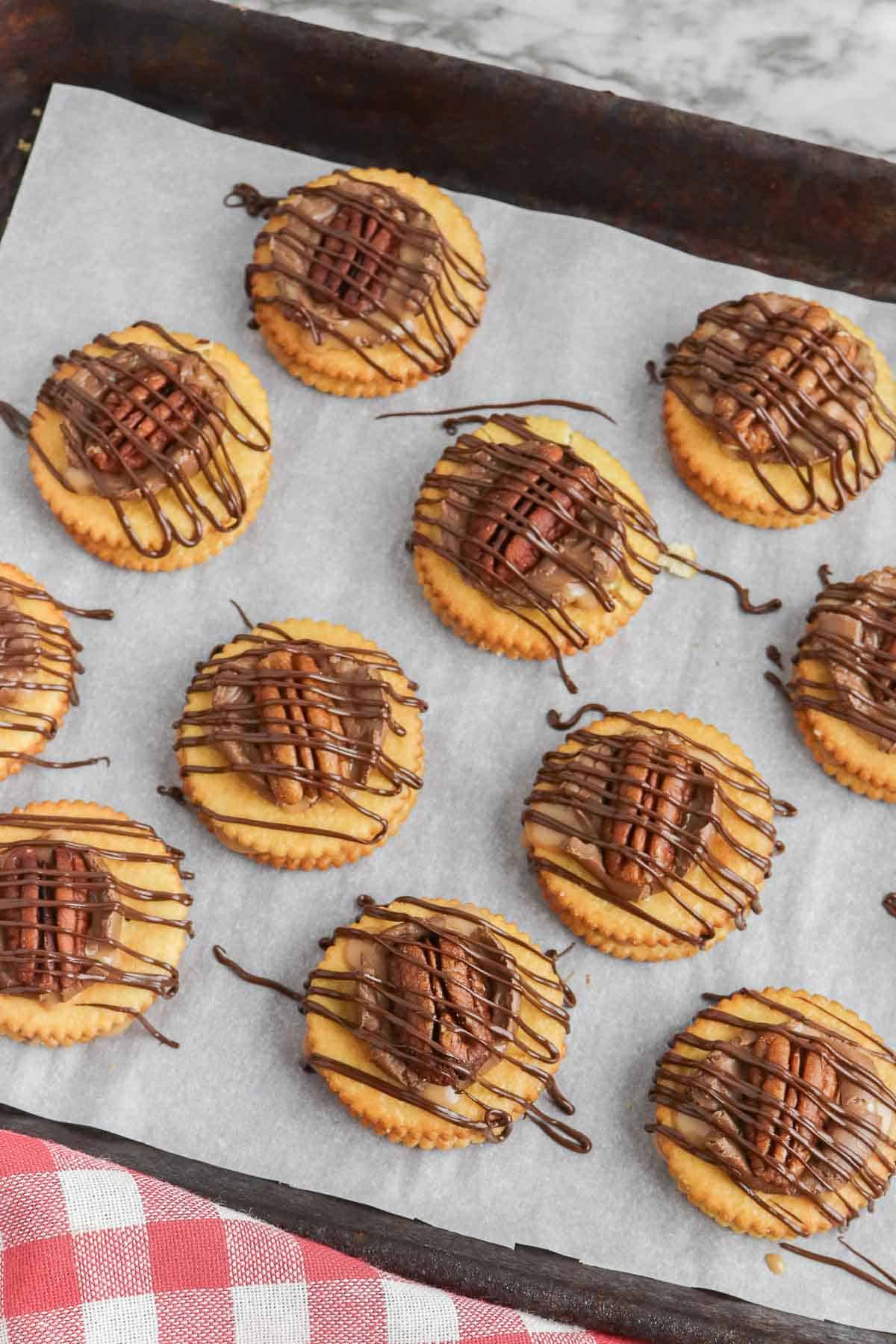A tray of cookies with chocolate drizzle and pecan halves on them.