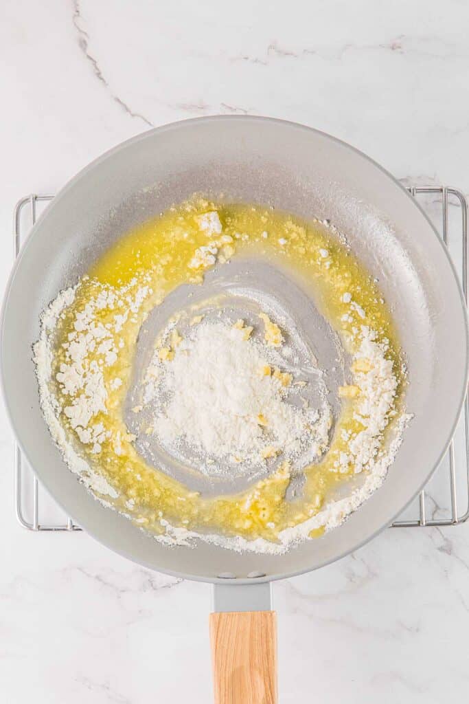 A frying pan with butter and flour being melted and mixed together.
