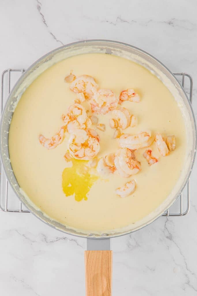 A large pan with shrimp and scallops in a cheese sauce.