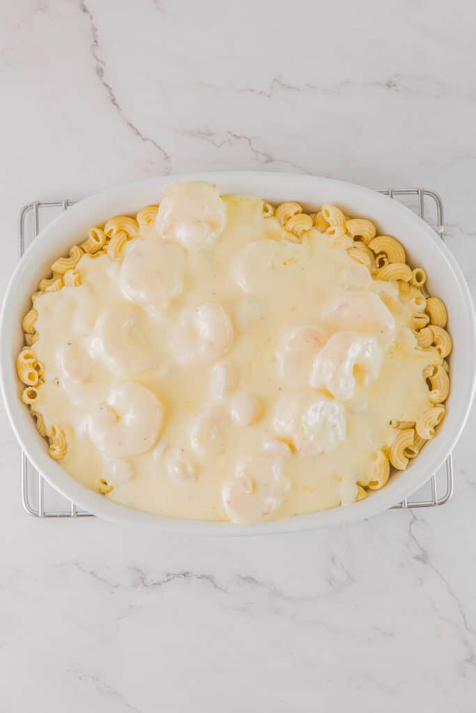 Macaroni and cheese with shrimp and scallops in a white dish.