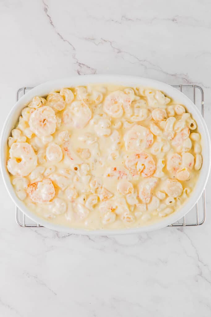 A white dish of macaroni and cheese with shrimp and scallops.