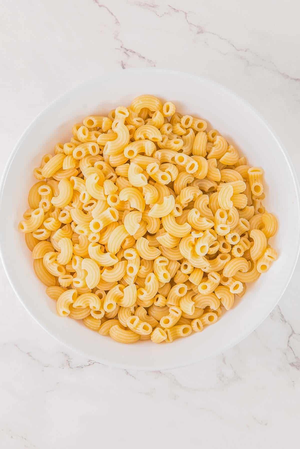 Elbow macaroni pasta in a white bowl.