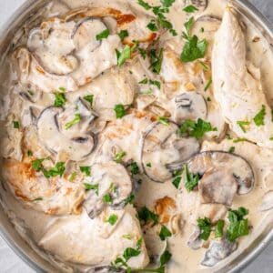 skillet full of creamy chicken with mushroom sauce topped with parsley.