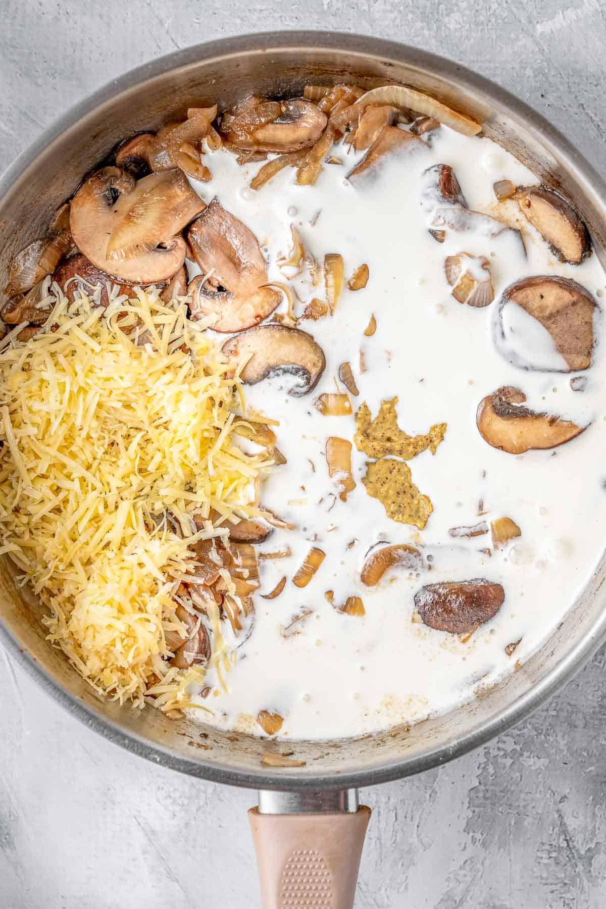 A pan with mushrooms, heavy cream and parmesan cheese in it.