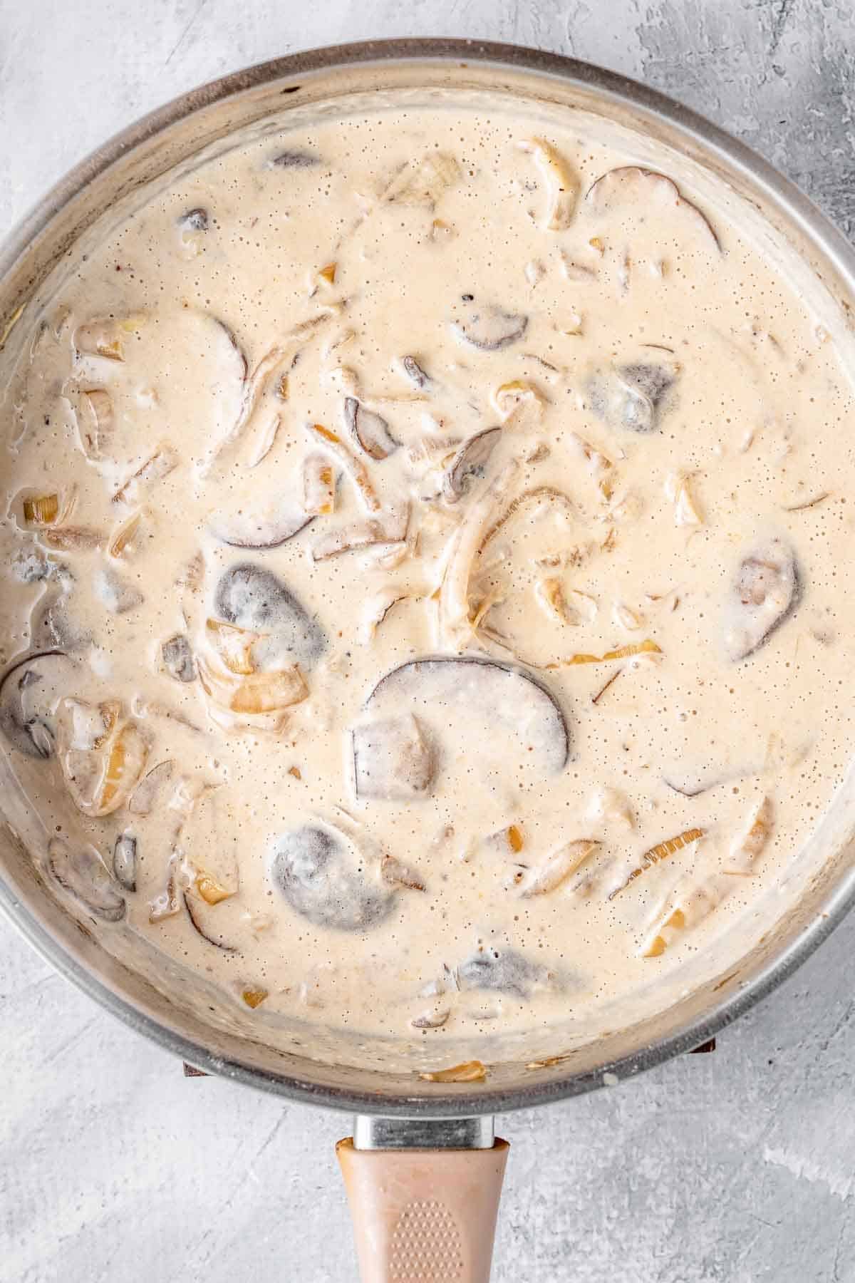 creamy mushroom sauce in a skillet with sautéed onions.