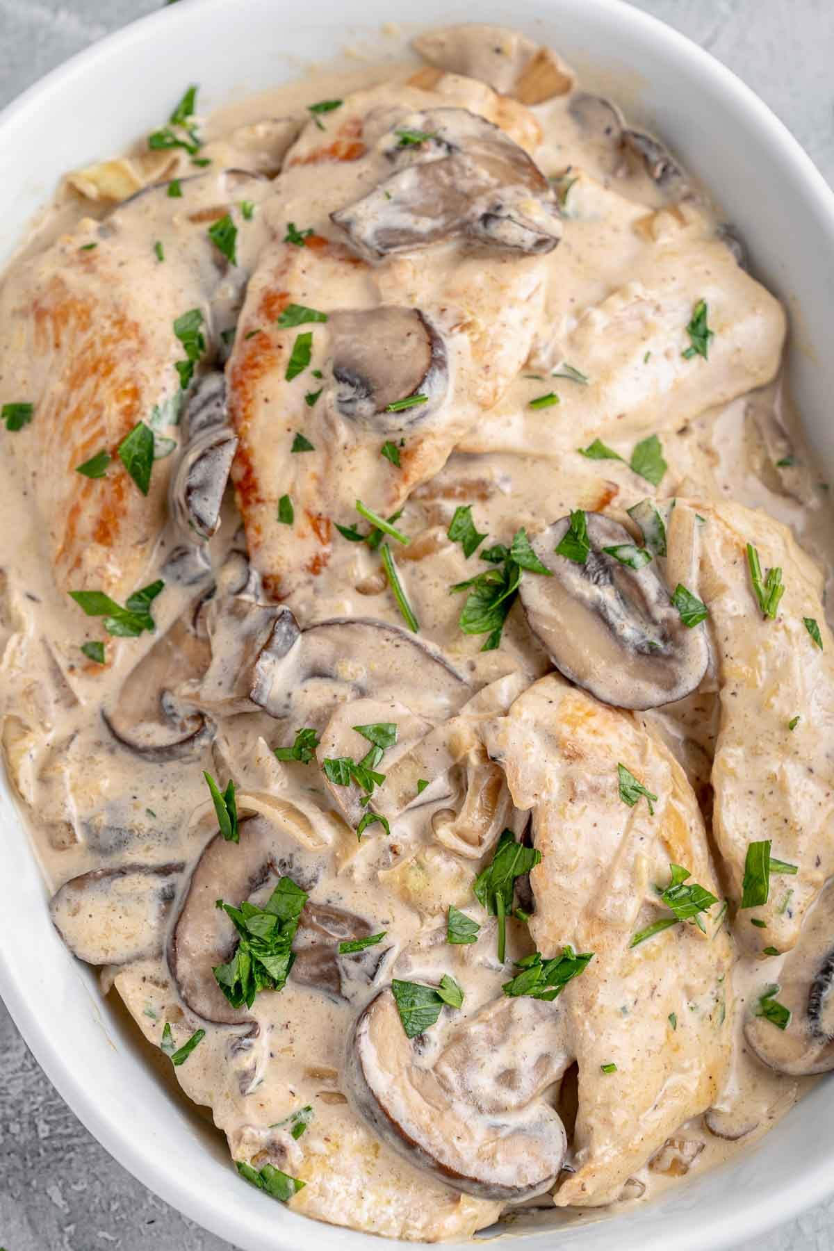 A white dish filled with chicken coated in a mushroom sauce.