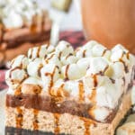 A slice of layered no-bake chocolate oreo delight recipe topped with mini marshmallows and chocolate syrup on a white plate.