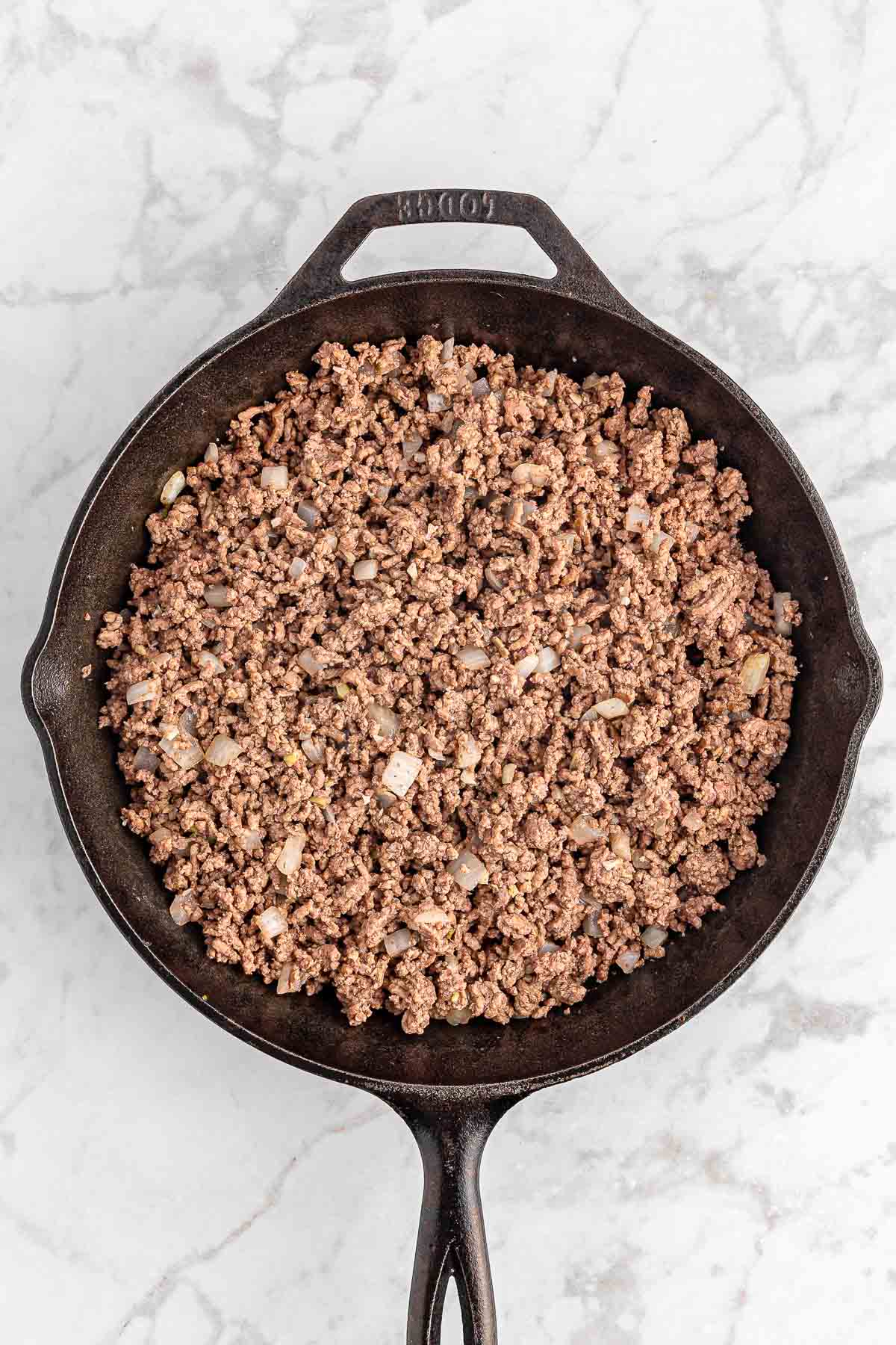 A cast iron skillet filled with ground beef.