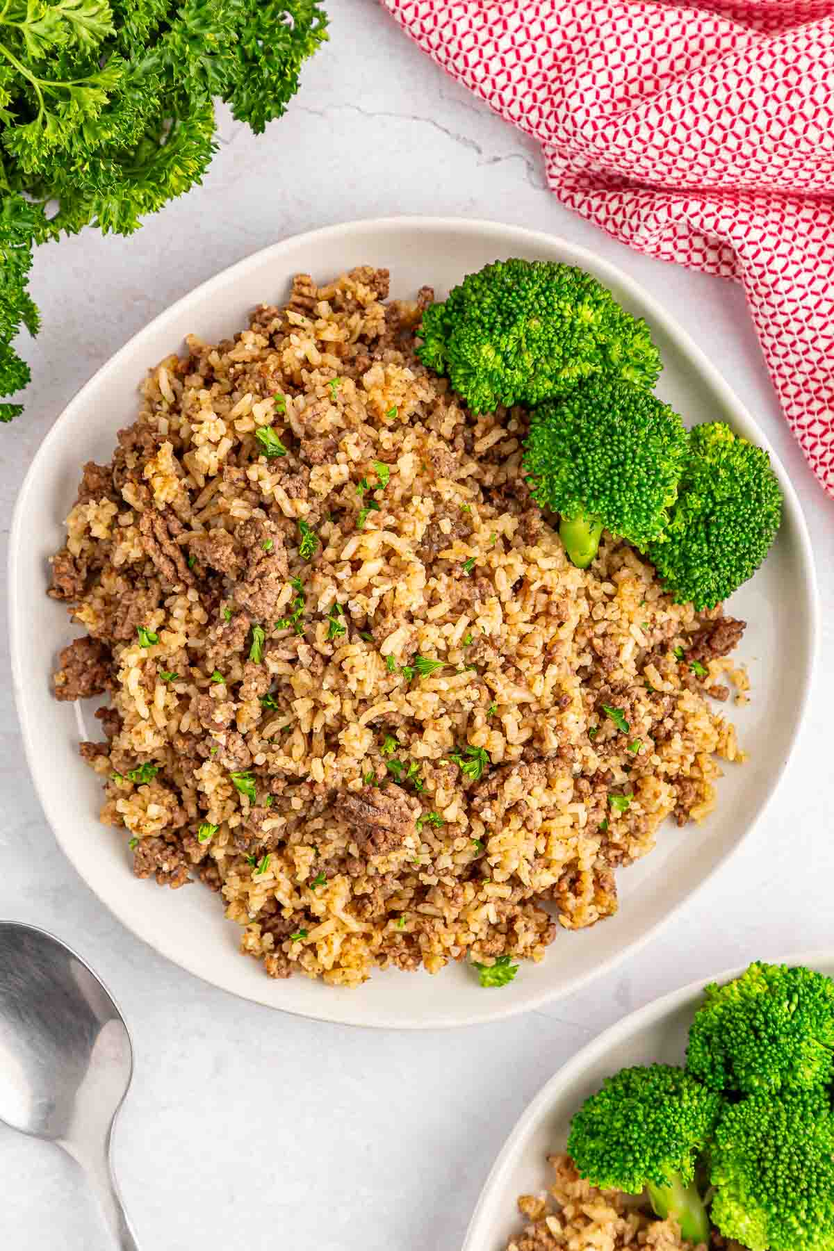 bowl of hamburger rice casserole with broccoli florets on the side.
