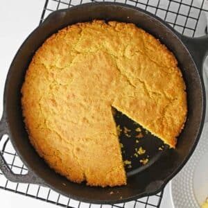 southern cornbread recipe in a cast iron skillet with a slice taken out.