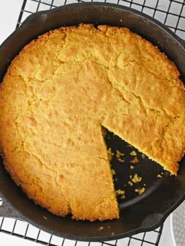 southern cornbread recipe in a cast iron skillet with a slice taken out.