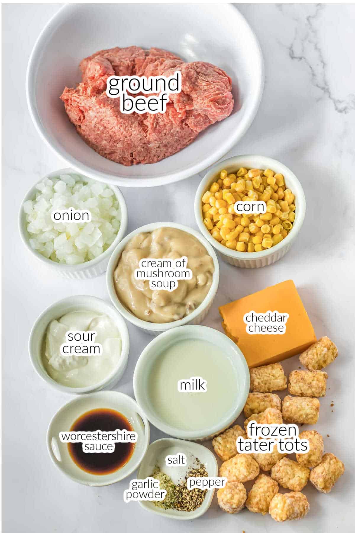 The ingredients for tater tot casserole in bowls. ground beef, corn, cream of mushroom soup, onions, milk, sour cream, frozen tater tots, cheese, worcestershire sauce