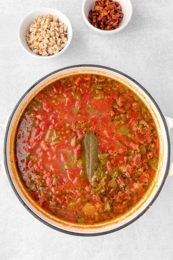 A pot full of chowder with clams, tomatoes, and potatoes on a table.