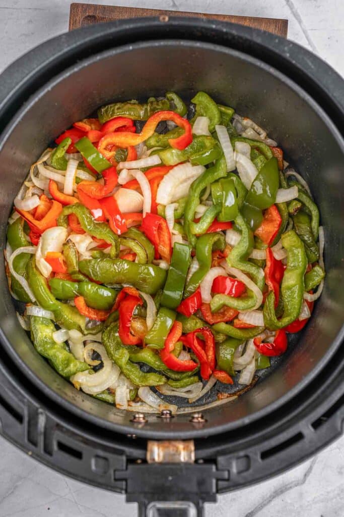 An air fryer filled with peppers and onions.