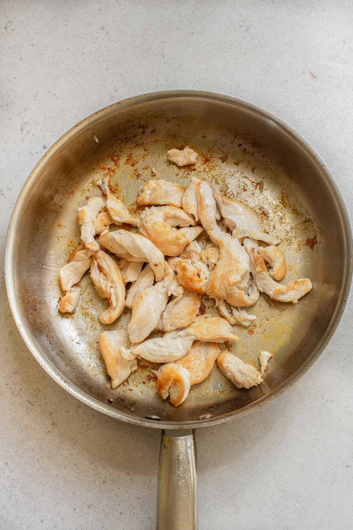chicken strips cooking in a frying pan.