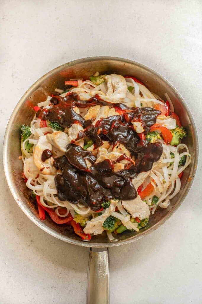 A frying pan filled with rice noodles and sauce.