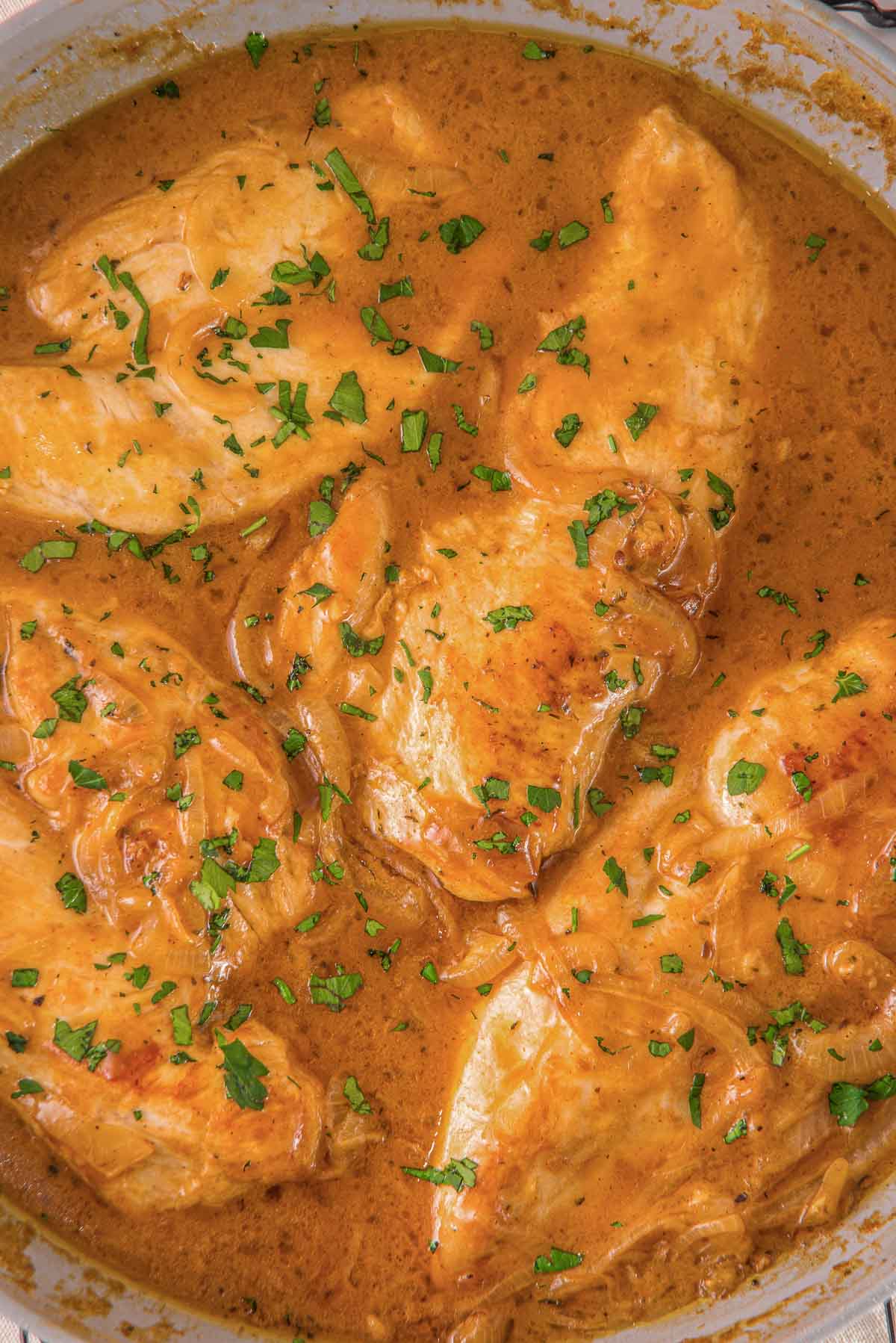 A skillet full of an easy smothered chicken recipe in a creamy sauce.