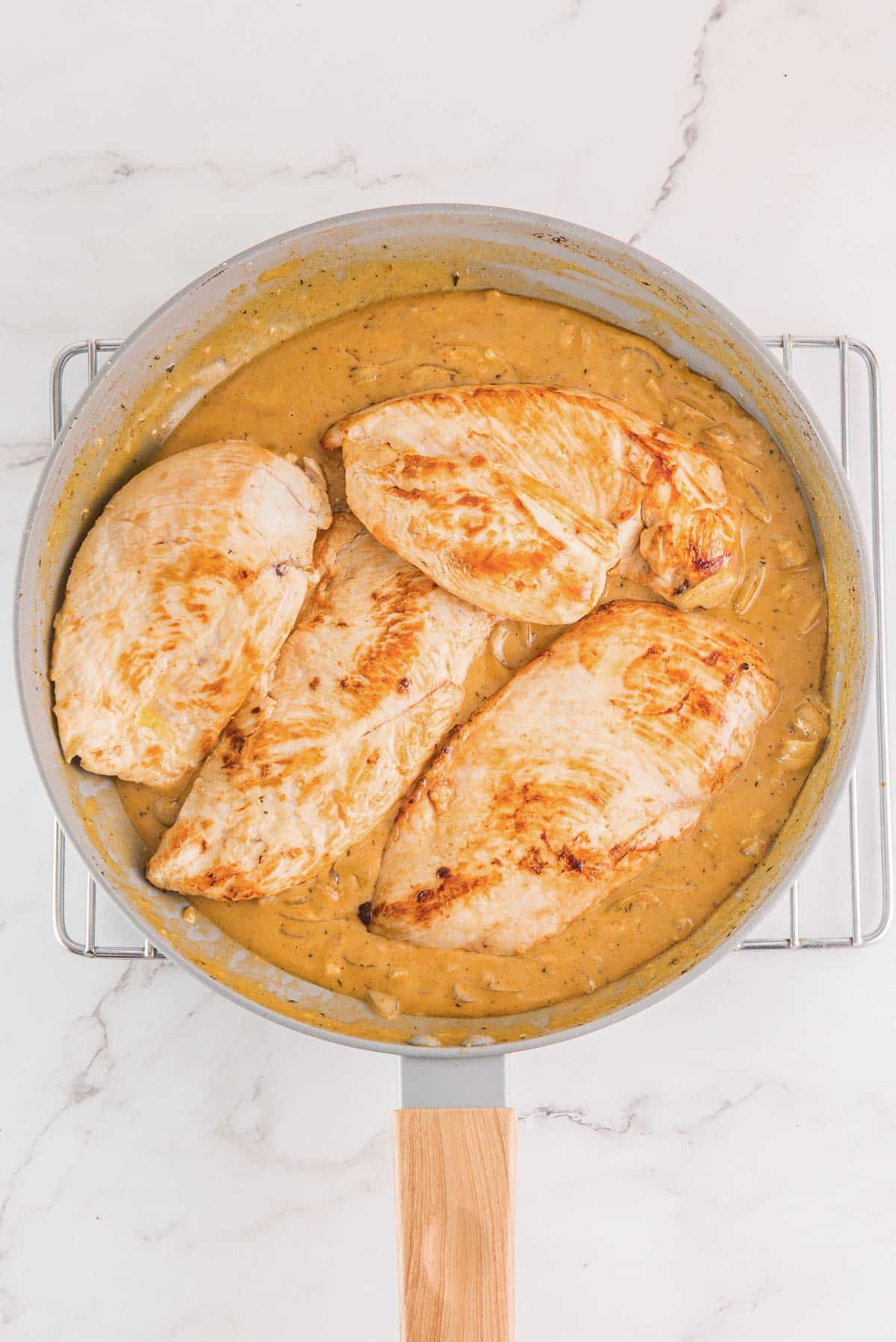 cooked chicken breasts in creamy onion gravy in a pan.