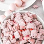 Strawberry muddy buddies in a bowl on a white plate.