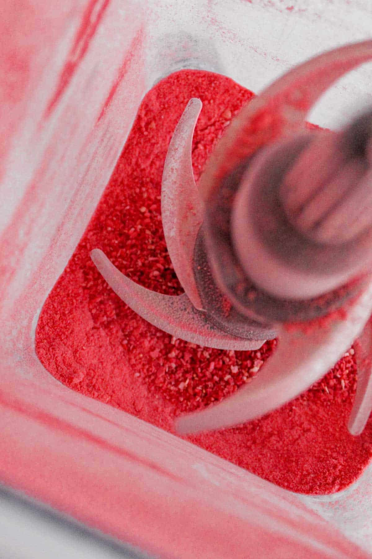 A blender with blended freeze dried strawberries blended to a powder.