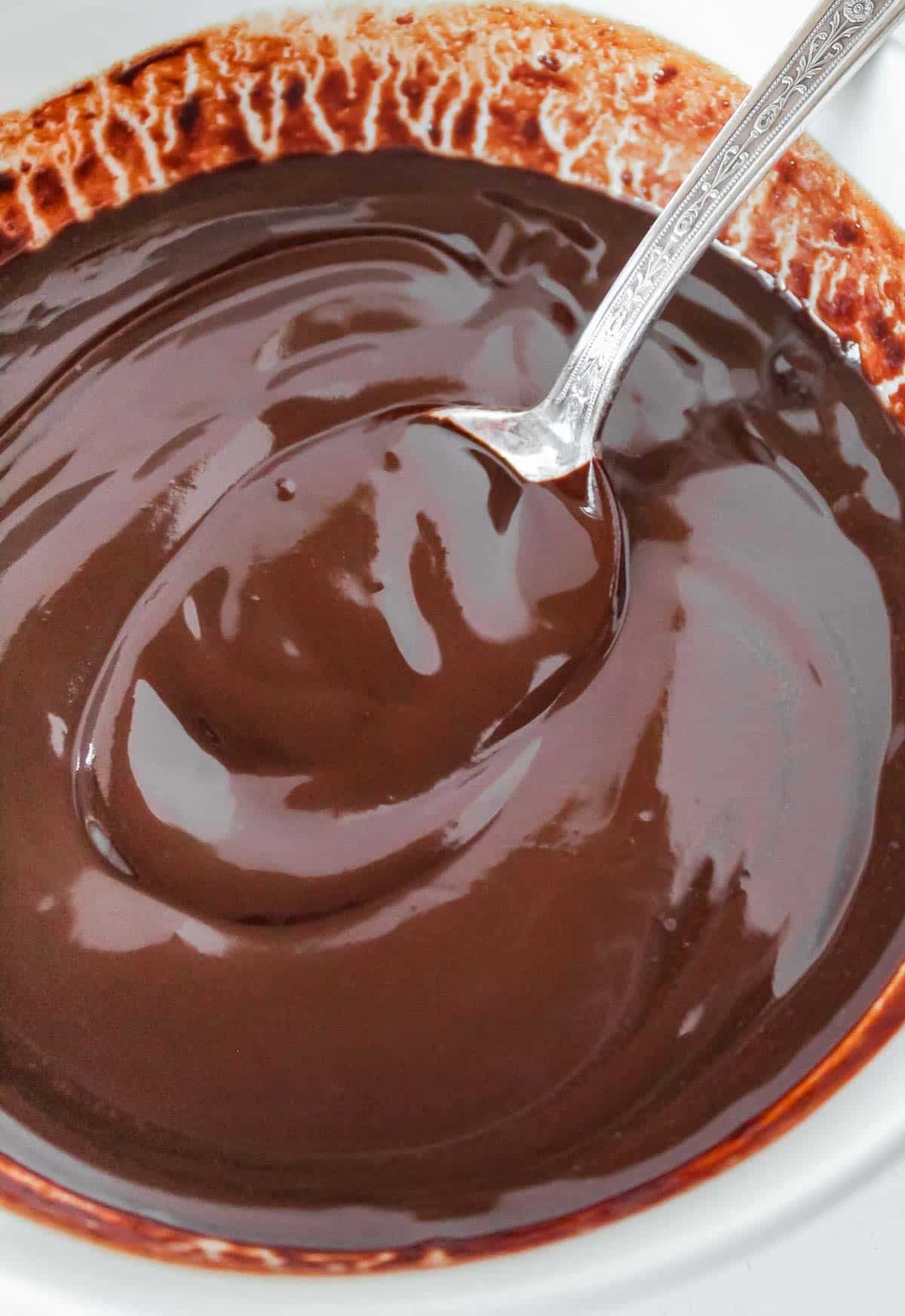 Chocolate sauce in a bowl with a spoon.