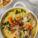 A bowl of easy creamy tuscan chicken soup with carrots, spinach and sun dried tomatoes and a spoon.