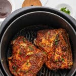 Two air fryer chicken thighs in an air fryer.