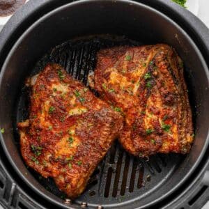 Two air fryer chicken thighs in an air fryer.