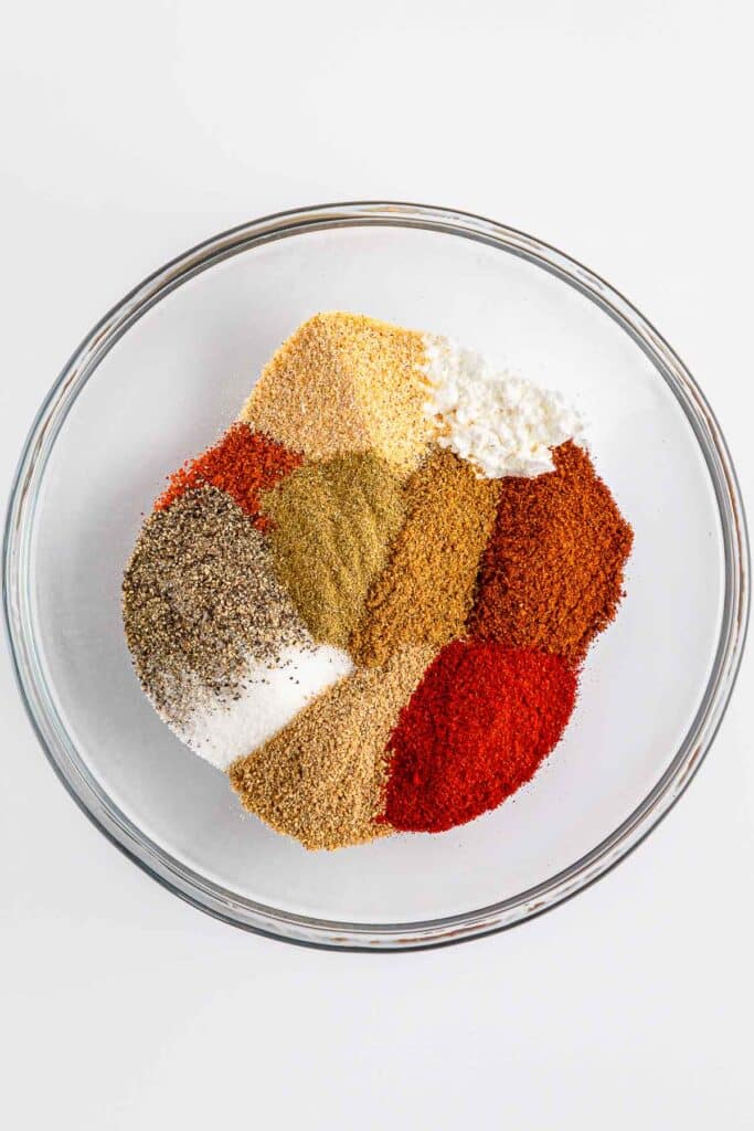 A large glass bowl of seasonings ready to be mixed together.