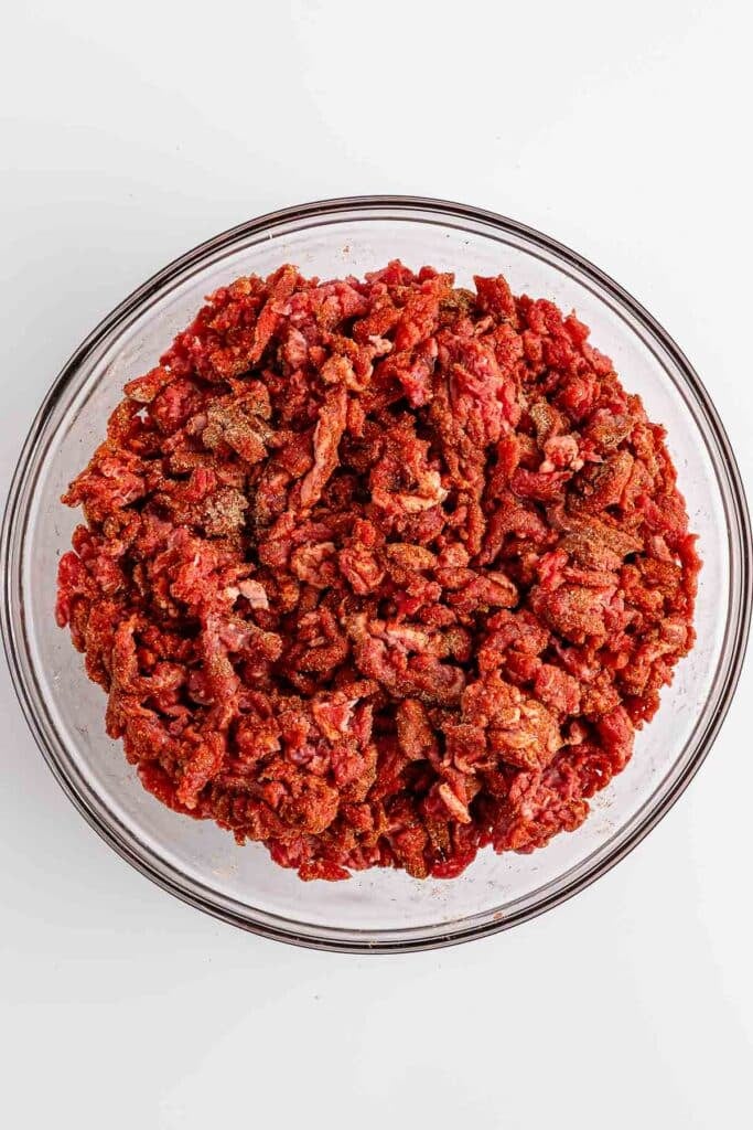Red meat in a large clear bowl.