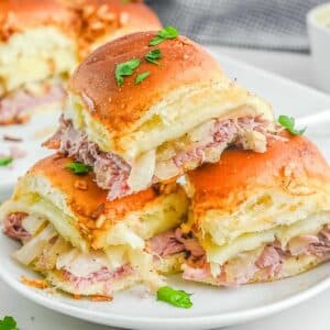A stack of french dip sliders on a white plate.