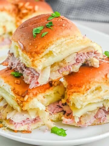 A stack of french dip sliders on a white plate.