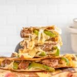 A stack of steak quesadillas on a wooden cutting board.