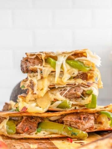 A stack of steak quesadillas on a wooden cutting board.