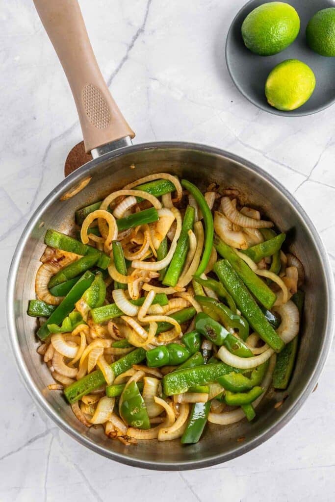 A pan with onions and green peppers in it.