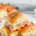 Stack of french dip sliders on a white plate.