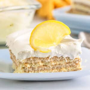 A piece of lemon icebox cake with a lemon slice garnish on a white plate.