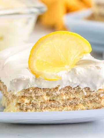 A piece of lemon icebox cake with a lemon slice garnish on a white plate.