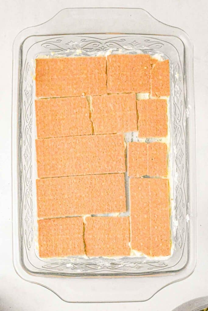 Graham cracker laid overtop of the filling mixture in a glass baking dish.