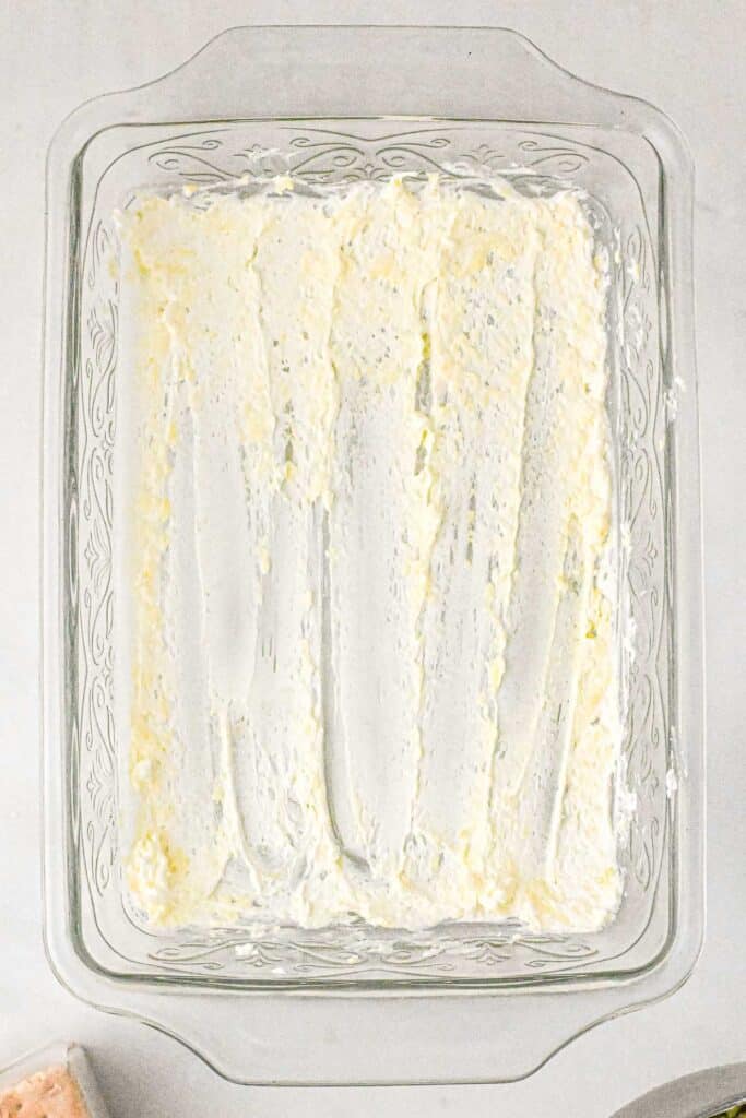 A glass baking dish containing a layer of the filling mixture spread evenly.