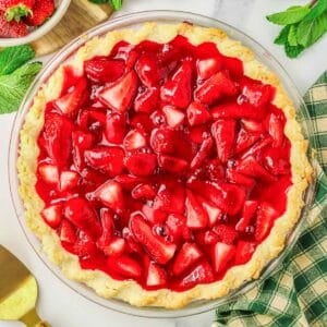A strawberry pie in a large glass pie plate.