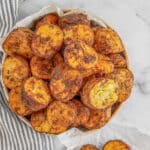 Air fryer potatoes in a bowl with a side of potatoes on a napkin.