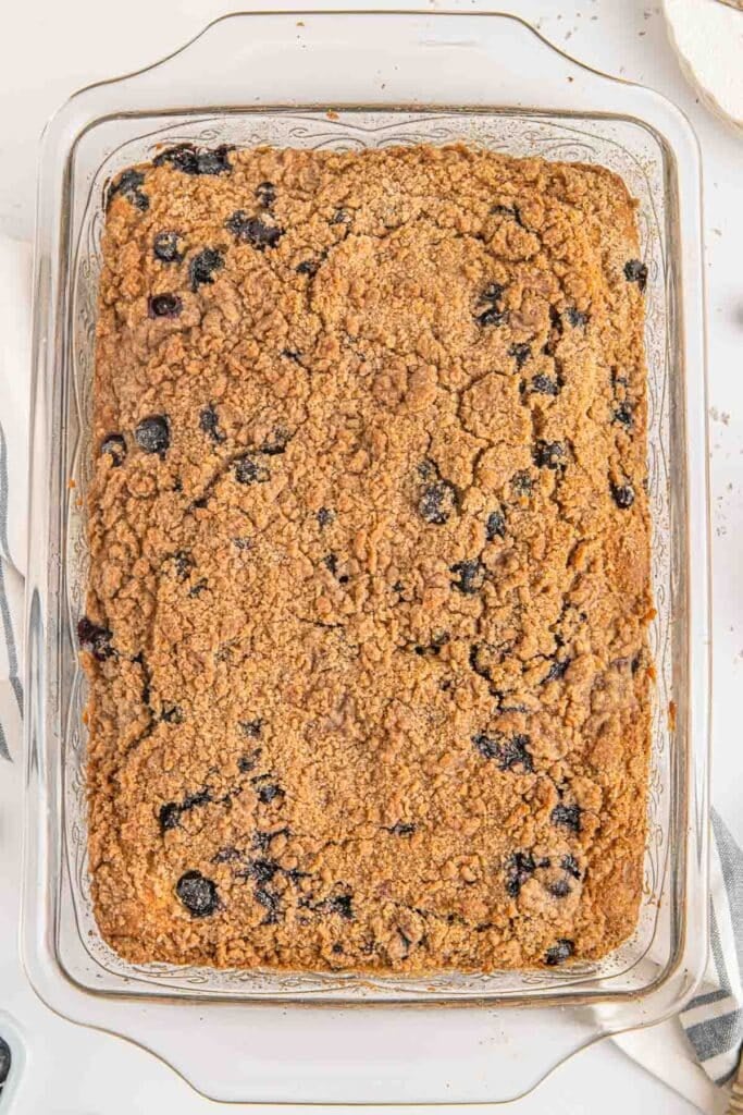A blueberry buckle with streusel topping in a clear glass baking dish.