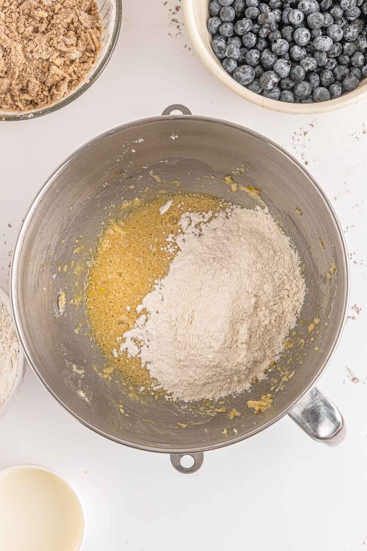 Flour mixture added with other ingredients in a metal mixing bowl.
