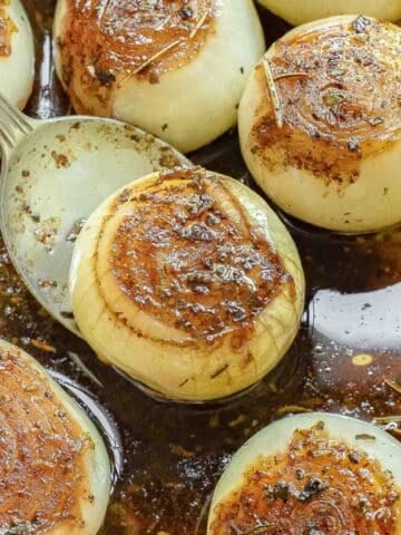 Baked onions in a baking dish, topped with a caramelized seasoning with a balsamic and butter sauce.