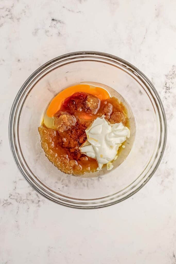 A clear glass bowl with all wet ingredients added ready to be mixed.