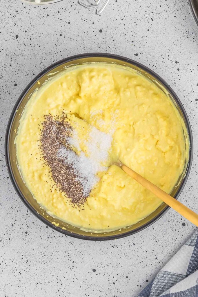 Salt and pepper added to hard boiled egg mixture in a large mixing bowl.